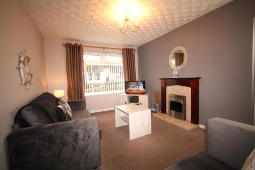 a living room with a couch and a fireplace at Heulwen - Moelfre in Moelfre