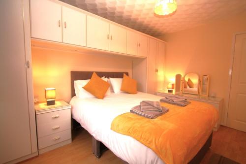 a bedroom with a large bed with orange pillows at Heulwen - Moelfre in Moelfre