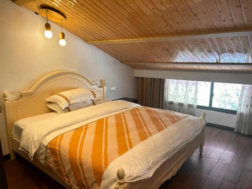 1 dormitorio con 1 cama con edredón de rayas naranja y amarillo en Family Hotel Zhangjiajie, en Zhangjiajie