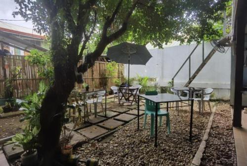 une table et des chaises sous un arbre avec un parasol dans l'établissement Royal Duchess Pension, à Puerto Princesa