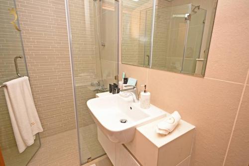 a bathroom with a white sink and a shower at Sunshine pool view 1BR apartment in Abu Dhabi