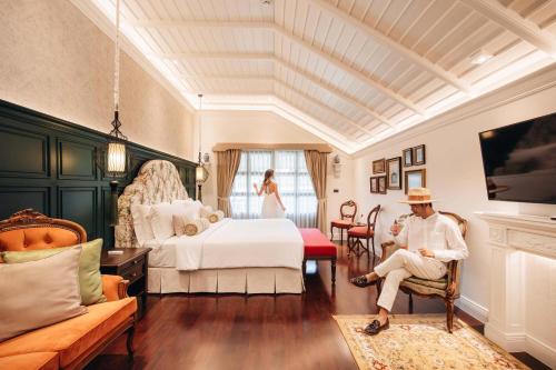 a man sitting in a chair in a bedroom at Na Nirand Romantic Boutique Resort in Chiang Mai