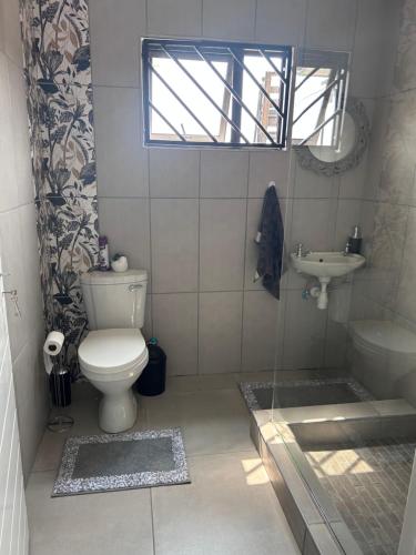 łazienka z toaletą, umywalką i oknem w obiekcie Ju’s Self-catering Accommodation w mieście Okakarara