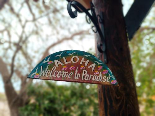 a sign on a wooden pole with a welcome to paradise at Magic Bus in Chlorakas