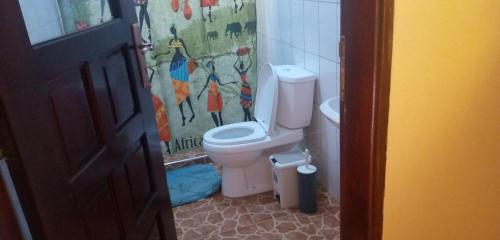 łazienka z toaletą i zasłoną prysznicową w obiekcie Lycklama Guesthouse w mieście Jinja