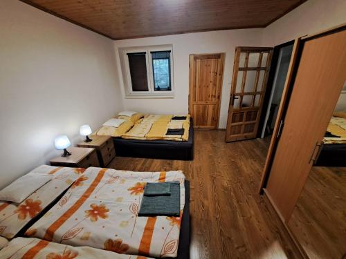 Habitación con 3 camas y suelo de madera. en Chalupa pod bralom, 