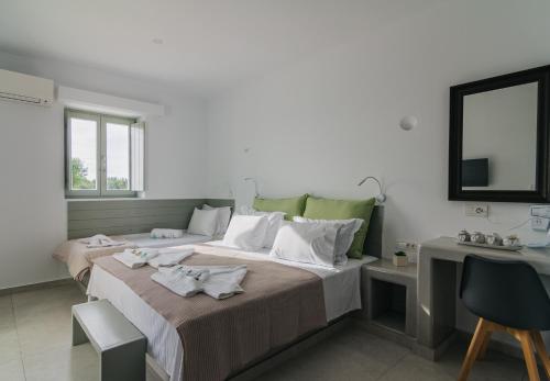 a bedroom with two beds and a table and a mirror at Olive Garden Luxury Resort in Angairiá