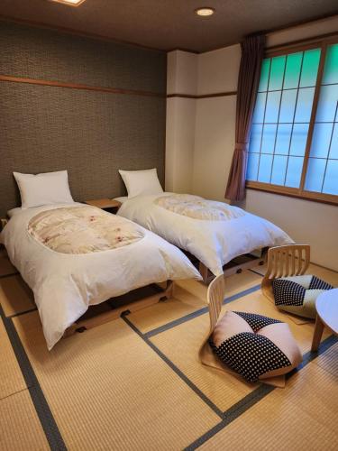 two beds in a room with two chairs at Hakuba Hotel Hana-no-Sato in Hakuba