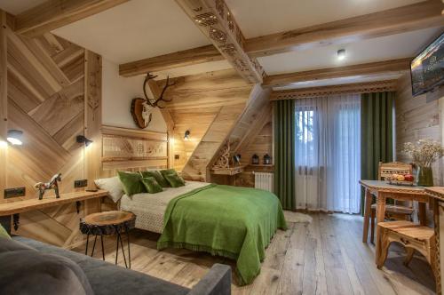 a bedroom with a green bed and wooden walls at Apartamenty u Grażyny in Murzasichle