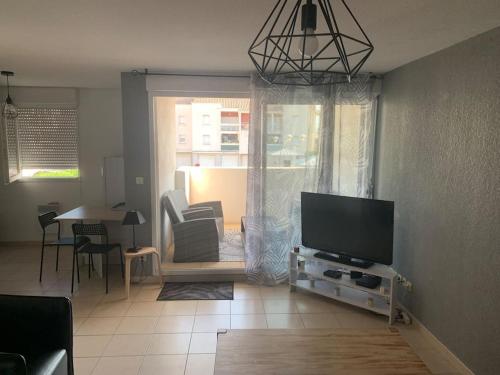 ein Wohnzimmer mit einem Flachbild-TV und einem Tisch in der Unterkunft Appartement T2 lumineux in Frontignan