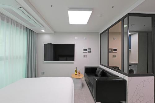a bedroom with a bed and a couch and a tv at Elmomento Gwangan in Busan