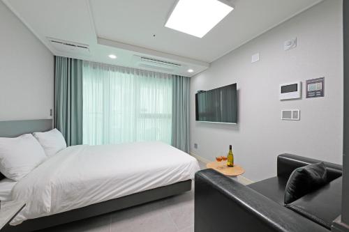 a bedroom with a white bed and a couch at Elmomento Gwangan in Busan