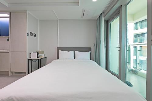 a large white bed in a room with a window at Elmomento Gwangan in Busan