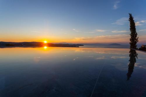 a view of the sunset from a swimming pool at Villa Mamasana - New Magnificent Villa with Infinity Pool & Tennis! in Kilada