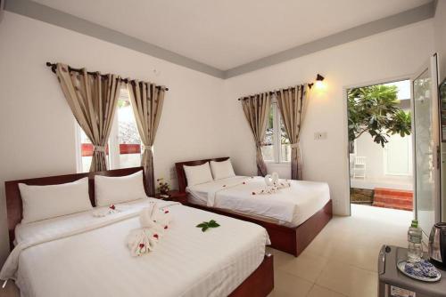 1 dormitorio con 2 camas con flores en Nu Cuoi Mui Ne Hotel & Restaurant, en Phan Thiet