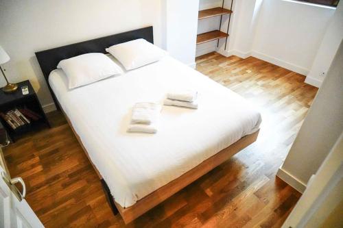 Cette chambre comprend un lit avec des draps blancs et du parquet. dans l'établissement Le Rive Hugo • Élégance & Art de vivre, à Châteauroux