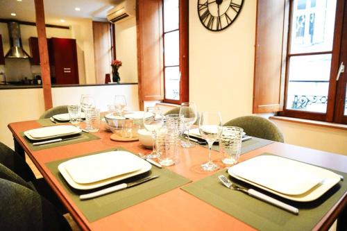 une table avec des verres et des serviettes et une horloge sur le mur dans l'établissement Le Rive Hugo • Élégance & Art de vivre, à Châteauroux