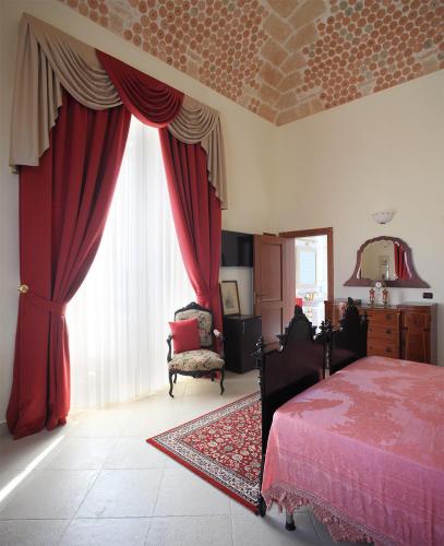 a bedroom with red curtains and a bed and a chair at Tenuta Lama Gorga in Trani