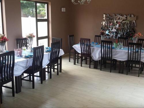 a dining room with a table and chairs with white table cloth at Emangweni Guest House in Vryheid