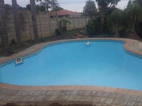 a large blue swimming pool in a yard at Emangweni Guest House in Vryheid