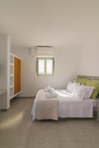 a bedroom with a bed with white sheets and a window at Olive Garden Luxury Resort in Angairiá