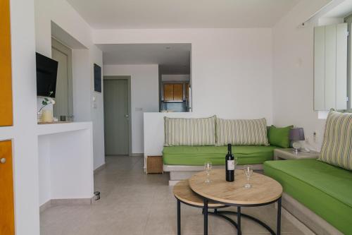 a living room with a green couch and a table with wine glasses at Olive Garden Luxury Resort in Angairiá