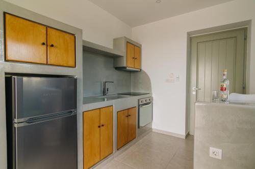 a kitchen with wooden cabinets and a stainless steel refrigerator at Olive Garden Luxury Resort in Angairiá
