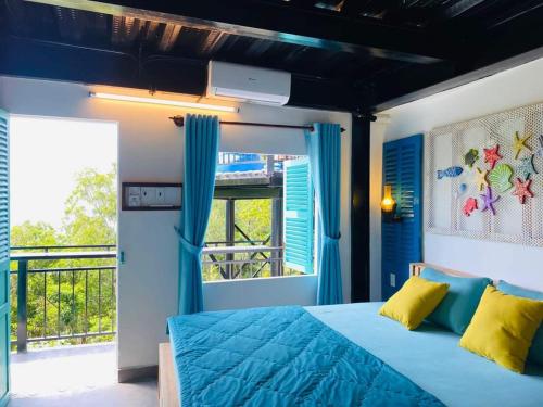 a bedroom with a blue bed and a balcony at THE NAM DU HILL in Nam Du
