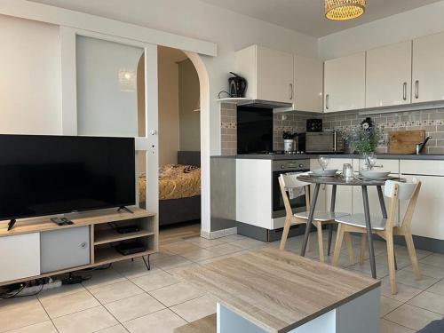 a kitchen and living room with a table and a television at Le Tranquille - Calme - Parking privé in Ambilly