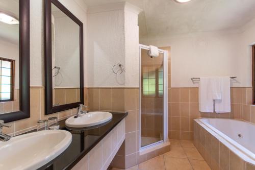 a bathroom with two sinks and a tub and a mirror at Kruger Park Lodge Unit No. 239 in Hazyview
