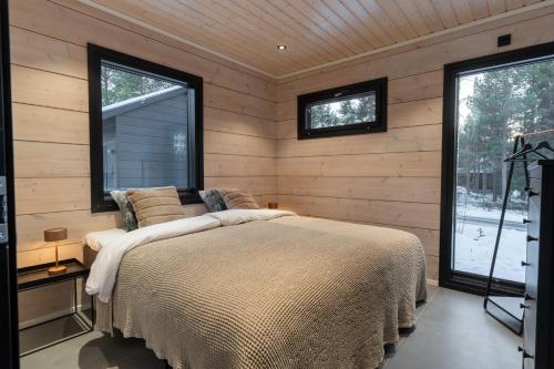 a bedroom with a large bed and two windows at Villa Ailo in Kittilä