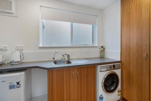 uma cozinha com um lavatório e uma máquina de lavar roupa em Sea View Timber Escape em Middleton
