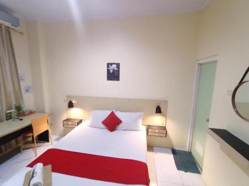 a bedroom with a large white bed with red pillows at Myplace Sario Manado in Manado