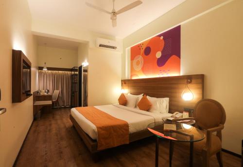 een hotelkamer met een groot bed en een tafel bij IRA by Orchid, Nashik in Nashik