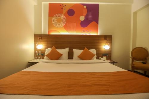 een slaapkamer met een groot bed met oranje kussens bij IRA by Orchid, Nashik in Nashik
