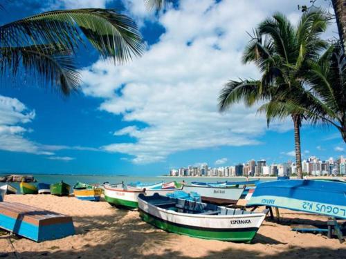 a group of boats on a beach with palm trees at Hotel da Praia in Vila Velha