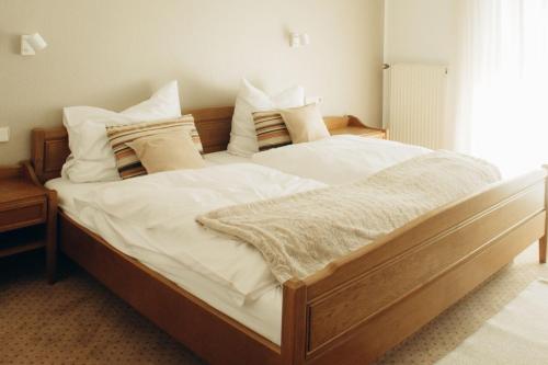 een slaapkamer met een groot bed met witte lakens en kussens bij The Resting Place in Lemgo