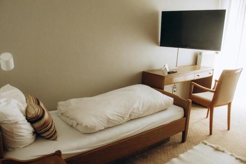 a bedroom with a bed and a desk with a television at The Resting Place in Lemgo