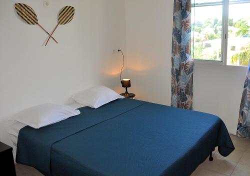 ein Schlafzimmer mit einem blauen Bett und einem Fenster in der Unterkunft Rêve d'Antan - Douceur exotique in Capesterre-Belle-Eau