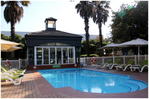 a pool with a gazebo with chairs and a lighthouse at Holiday Inn Johannesburg OR Tambo Airport Hotel by IHG in Kempton Park