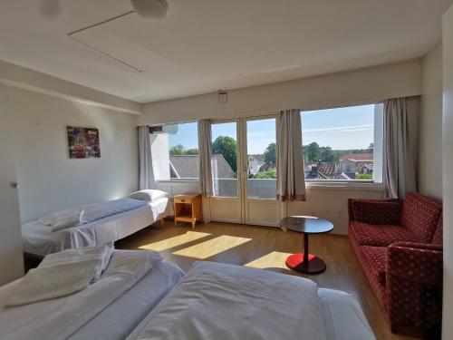 a room with two beds and a couch and a window at SKAP Hostel Mandal in Mandal