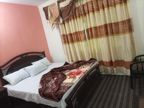 Cama en habitación con ventana y cortinas en Kaghan Valley Hotel, en Naran
