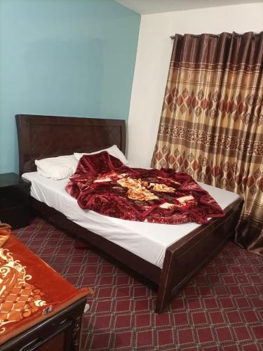 Una cama en una habitación con una manta roja. en Kaghan Valley Hotel, en Naran