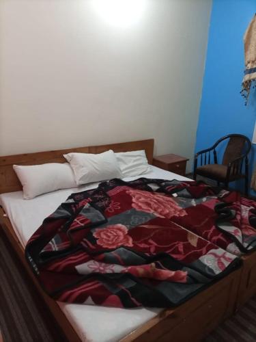 Una cama con una manta roja y negra. en Kaghan Valley Hotel, en Naran