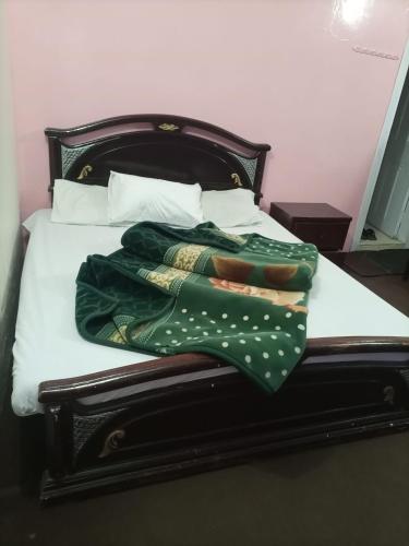 1 cama con manta verde y almohadas en Kaghan Valley Hotel, en Naran