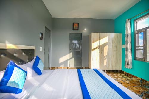 a bedroom with a large bed with blue and white pillows at The Bunksters Bir in Bīr