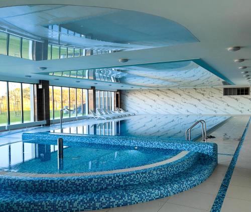 duży basen w budynku z niebieskimi płytkami w obiekcie Aurora Spa Nadmorskie Zacisze Dziwnów w Dziwnowie