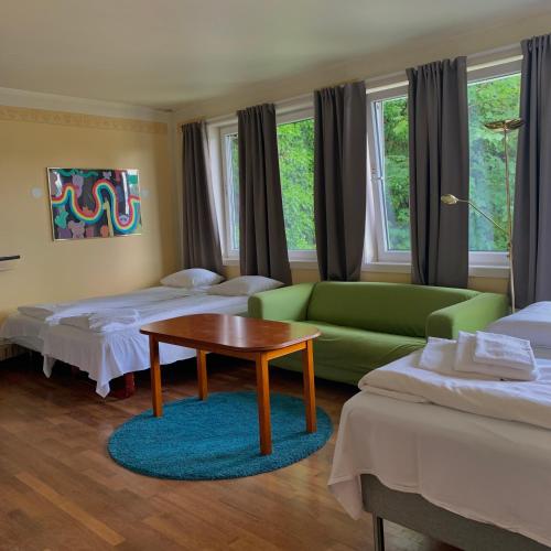 a room with two beds and a couch and a table at SKAP Hostel Mandal in Mandal