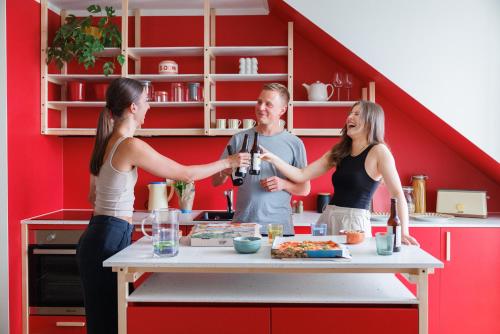 two women and a man standing in a kitchen holding a bottle of wine at POHA House Theaterplatz in Aachen