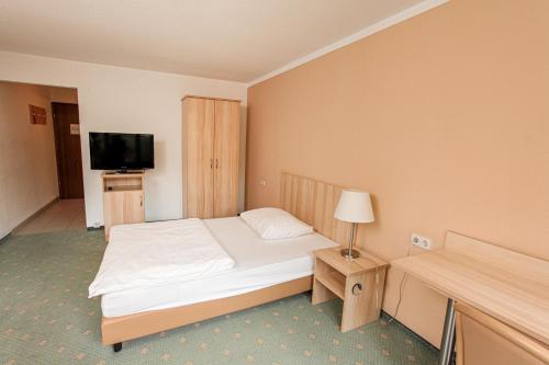 a hotel room with a bed and a television at Appartis - Boardinghouse am Klostersee in Sindelfingen